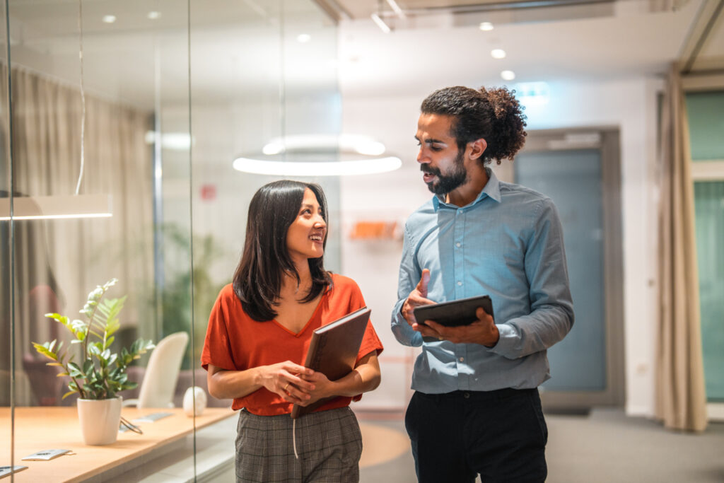 Colleagues walking and discussing work in a modern office, demonstrating the benefits of corporate empathy training and empathy in the workplace.