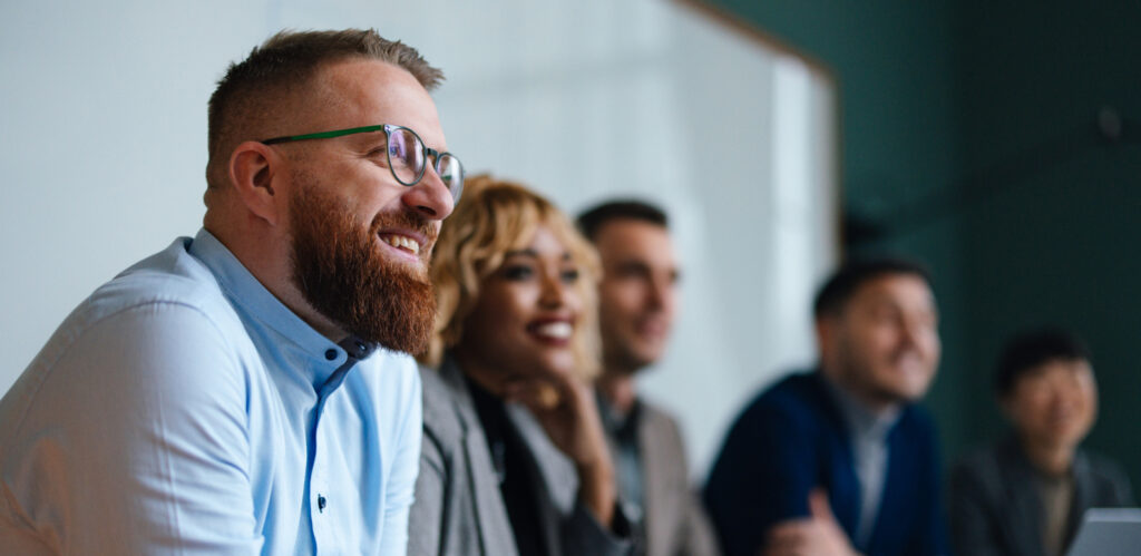 Smiling business professionals in a meeting, highlighting the positive impact of corporate empathy training and empathy training in the workplace