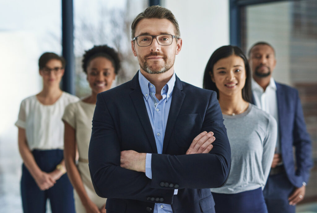 Confident business leader with diverse team, showcasing the impact of corporate empathy training and its benefits in the workplace.